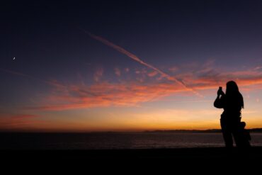 a person taking a picture of a sunset with a cell phone
