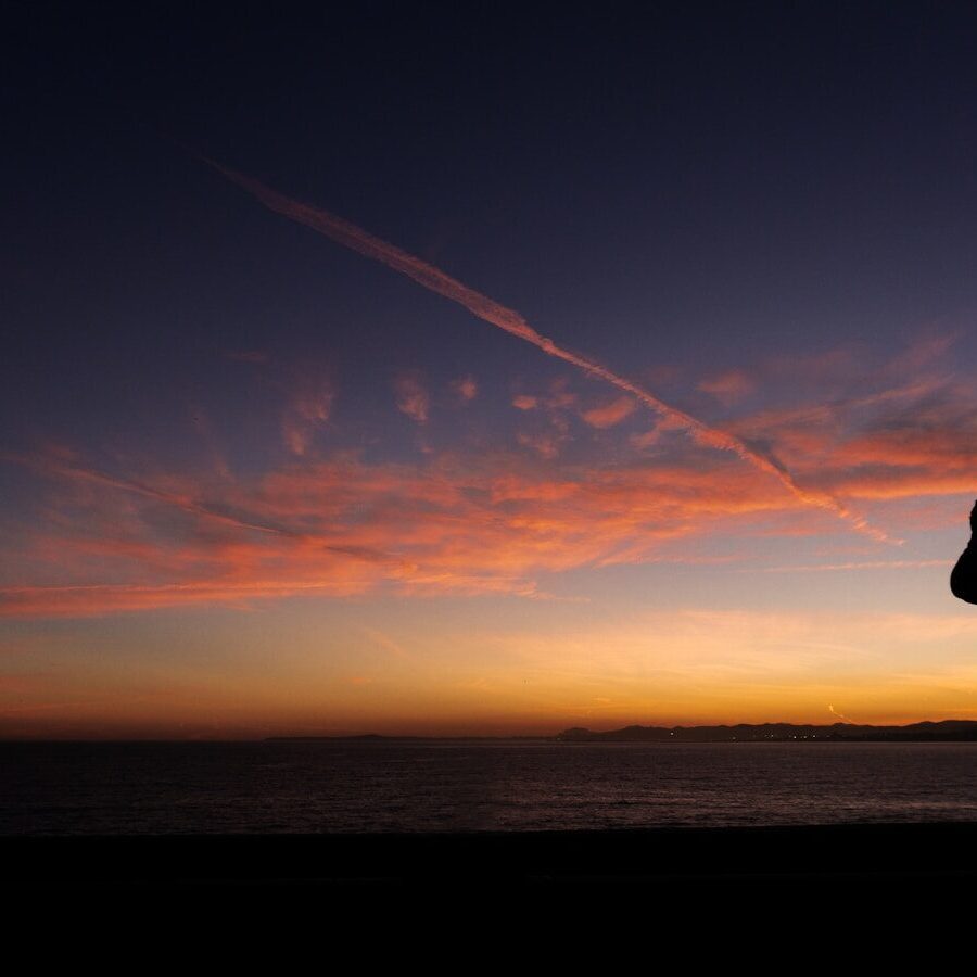 a person taking a picture of a sunset with a cell phone