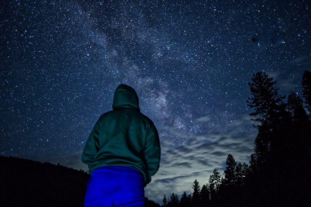 A person in a green jacket looking up at the night sky