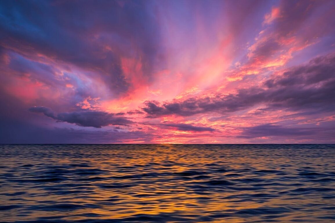 Stunning ocean view at sunset with colorful sky reflecting on the water.