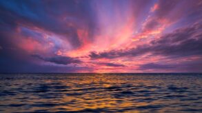 Stunning ocean view at sunset with colorful sky reflecting on the water.