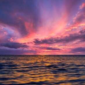 Stunning ocean view at sunset with colorful sky reflecting on the water.