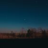 View through moving car window of horizon line with dark star sky and blurred trees
